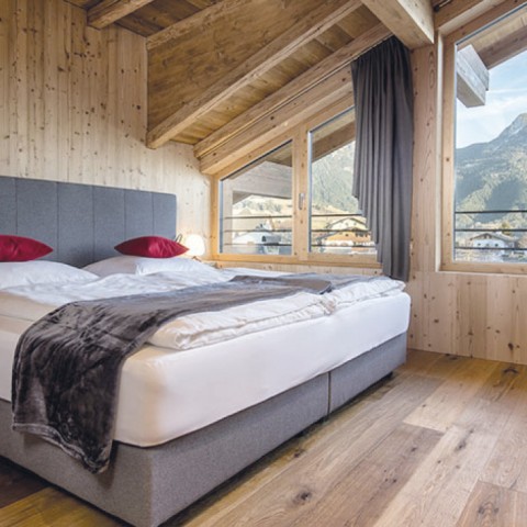 hubertus dolomites Fiè allo Sciliar | Confortevoli camere per rilassanti pernottamenti Una camera con letto e cuscini rossi.