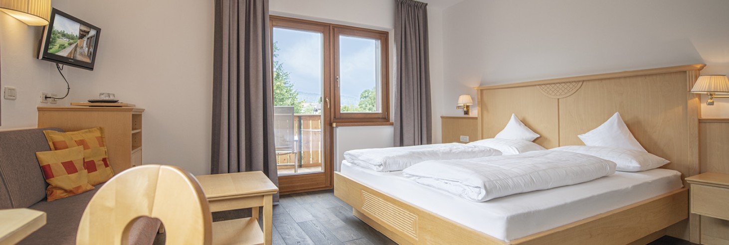 hubertus dolomites a Fiè allo Sciliar | La tua casa in montagna: camere sull'Alpe di Siusi. La camera comfort con un letto matrimoniale, un divano e una televisione. Attraverso la porta del balcone si può ammirare la vista diretta sulla natura.