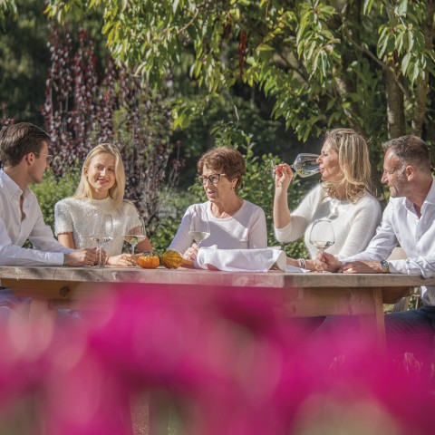 hubertus dolomites Völs am Schlern | Creare connessioni e conversazioni Tempo per famiglia nel giardino. Si godono il bel tempo e bevono un bicchiere di vino.