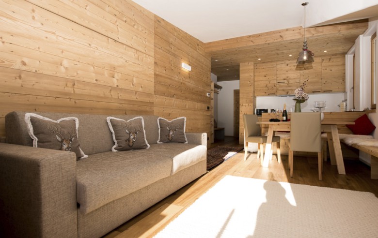 Accogliente divano sotto profumati rivestimenti in vero legno in uno chalet rustico e romantico per vacanze nella natura, direttamente sull'Alpe di Siusi.