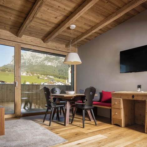 Il soggiorno di un appartamento con sedie nere e una televisione.