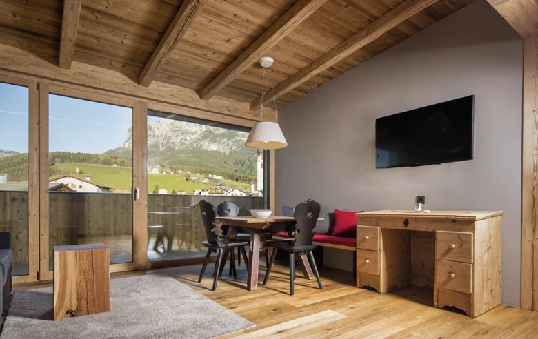 Il soggiorno di un appartamento con sedie nere e una televisione.