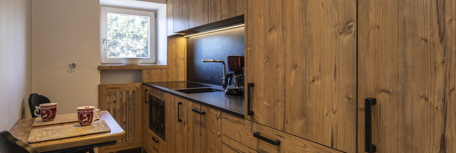 hubertus dolomites a fiè allo sciliar | relax e avventura: i nostri confortevoli appartamenti ai piedi dello sciliar. La cucina dell'appartamento vacanze. Si vede una cucina completamente attrezzata con un piccolo tavolo da pranzo e due sedie.