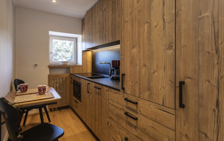 La cucina dell'appartamento vacanze. Si vede una cucina completamente attrezzata con un piccolo tavolo da pranzo e due sedie.