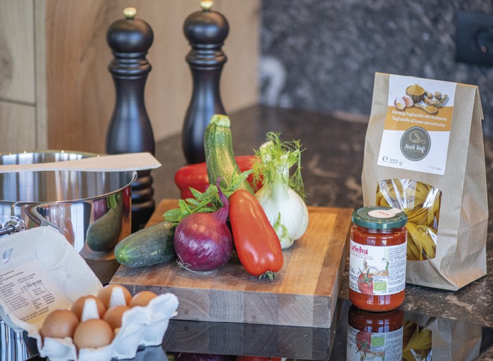 Una tavola con verdure, un pacco di pasta, salsa di pomodoro e uova.