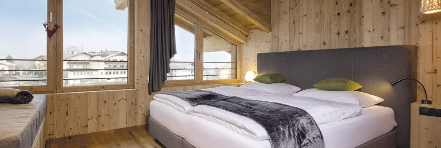 hubertus dolomites a Fiè allo Sciliar | Avventure in montagna e relax ai piedi dello Sciliar. Una camera matrimoniale con divano. È spaziosa e realizzata in legno.