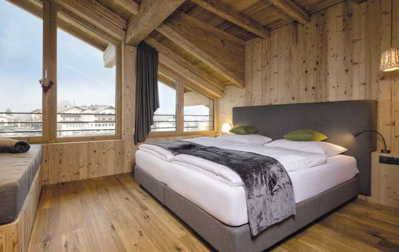 Una camera matrimoniale con divano. È spaziosa e realizzata in legno.