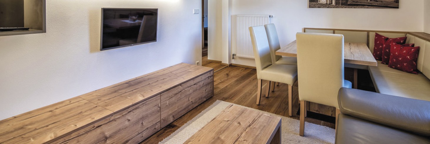 hubertus dolomites a fiè allo sciliar | Appartamenti vacanza con vista sullo Sciliar inclusa. La zona soggiorno con una televisione, un divano e un grande tavolo con sedie.