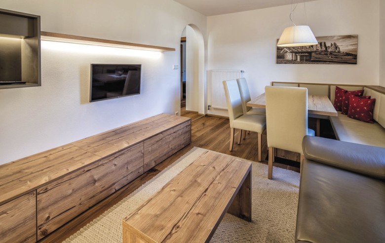 La zona soggiorno con una televisione, un divano e un grande tavolo con sedie.