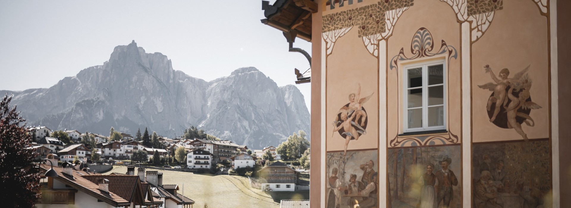 hubertus dolomites Fiè allo Sciliar | Avventura sull'Alpe di Siusi e ai piedi dello Sciliar Il villaggio die Fié sullo sfondo. In primo piano c'è una casa con una facciata particolare.