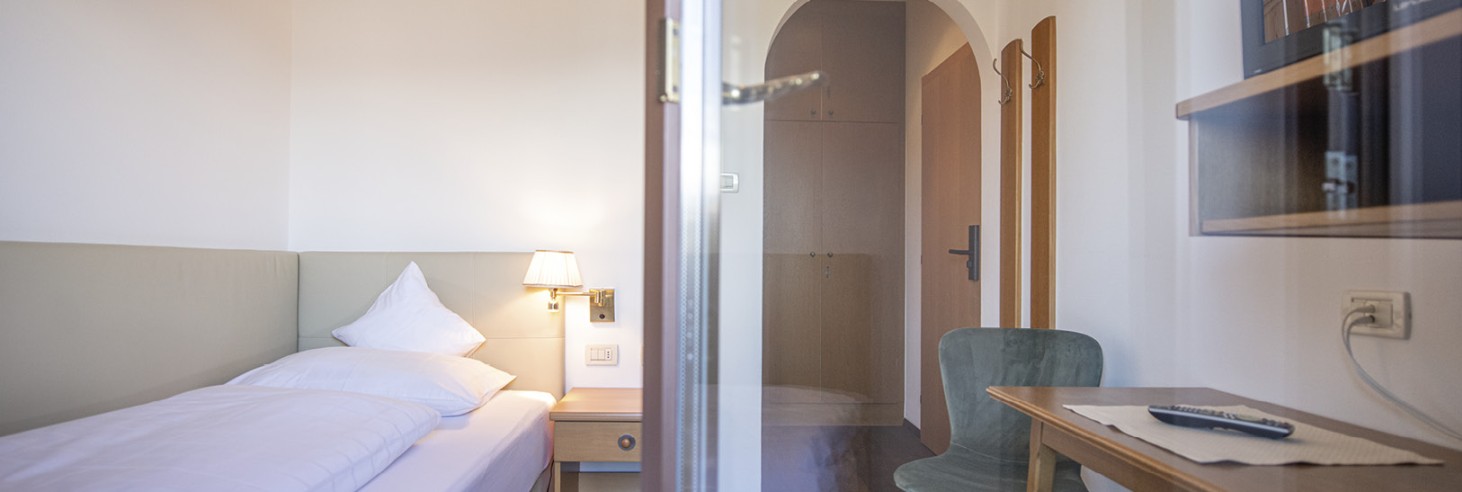 hubertus dolomites a Fiè allo Sciliar | Relax alpino puro: Le nostre camere sull'Alpe di Siusi sono perfette per i giovani. Un letto singolo con scrivania e televisore. La foto è stata scattata dal balcone.