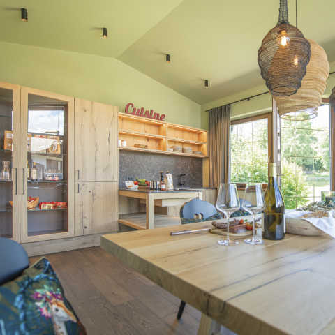 hubertus dolomites a fiè allo sciliar | Avventure allo Sciliar e pasti fatti in casa. L'immagine mostra la cucina comune con un tavolo apparecchiato. Sullo sfondo sono visibili prodotti dell'Alto Adige sulla zona cottura.