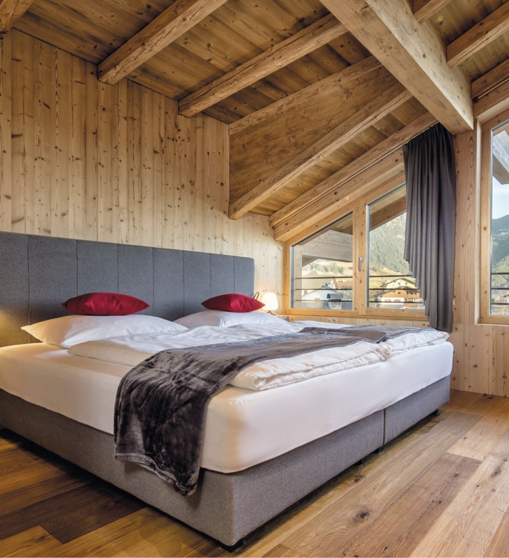 Una camera dell'Hubertus con un letto king size in legno antico.