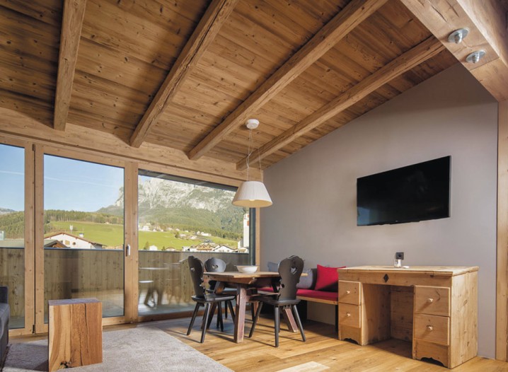 Il soggiorno di un appartamento con sedie nere e televisore.